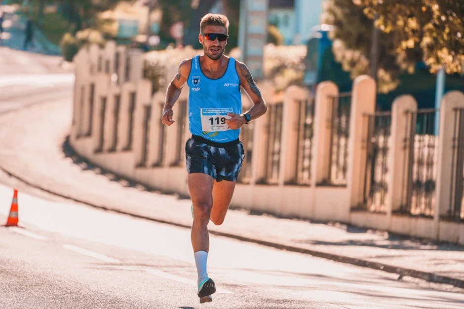 Male athlete running in an urban marathon under sunny conditions.