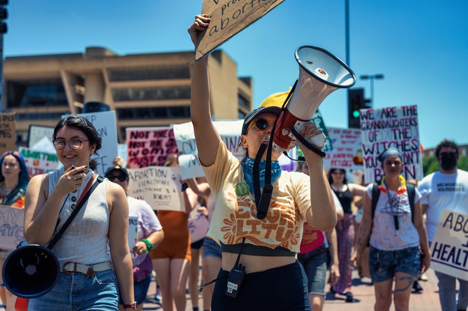 Diverse group of women advocating for rights during a peaceful protest, holding signs and megaphones.