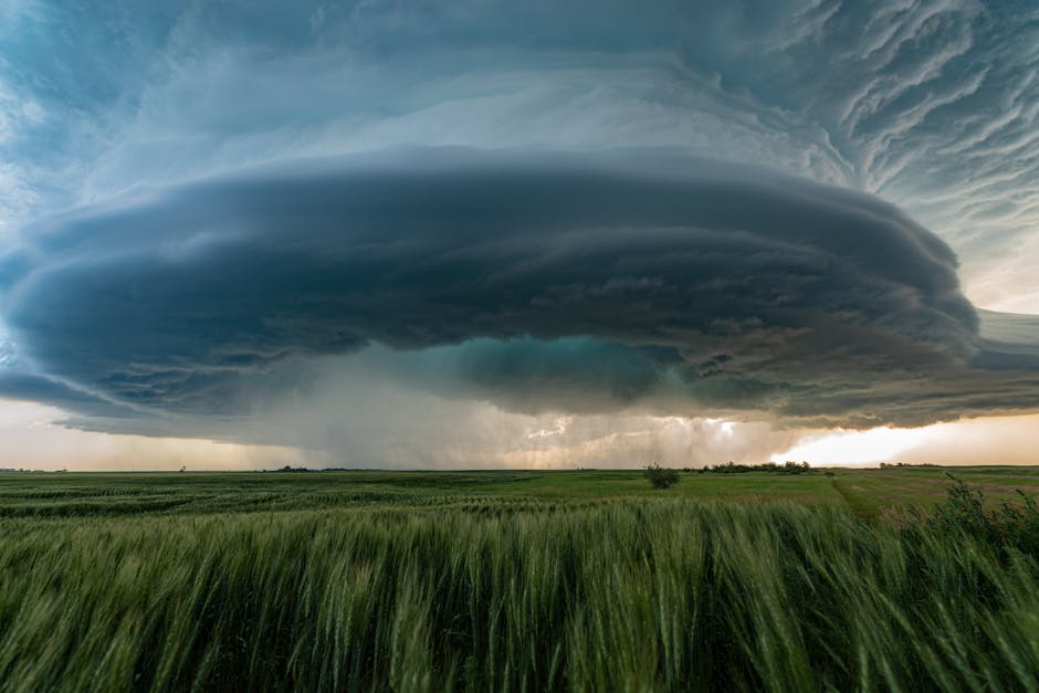 A powerful supercell storm looms over lush green fields in Saskatchewan, Canada.