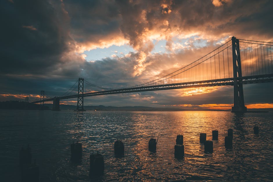 Stunning sunset view of the Bay Bridge in San Francisco reflecting on water.