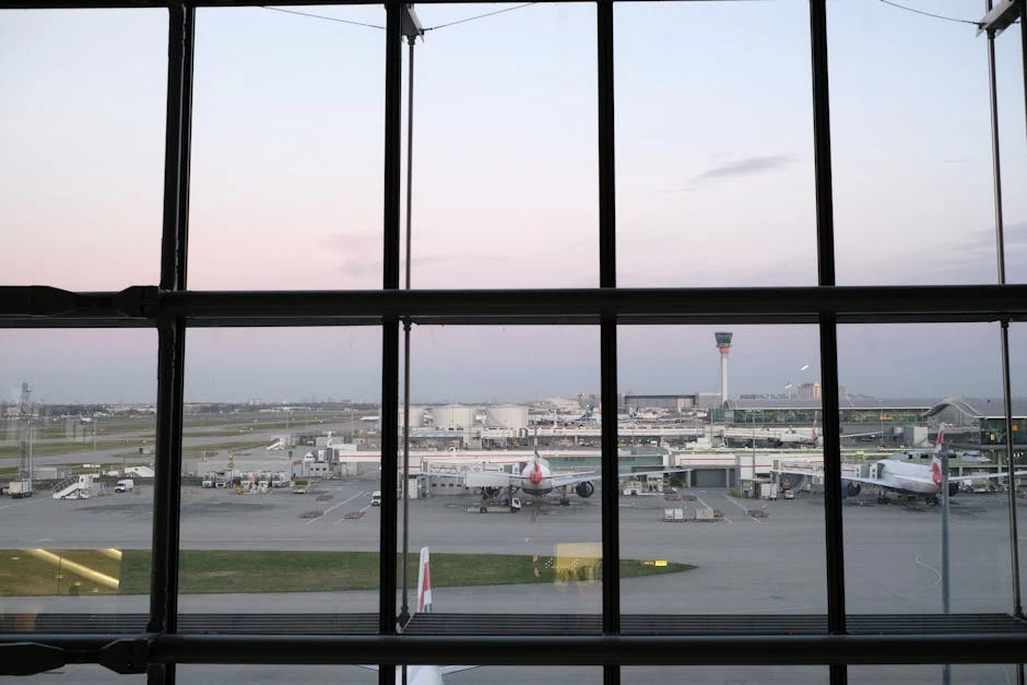 View of Heathrow Airport tarmac and airplanes through terminal window during twilight.