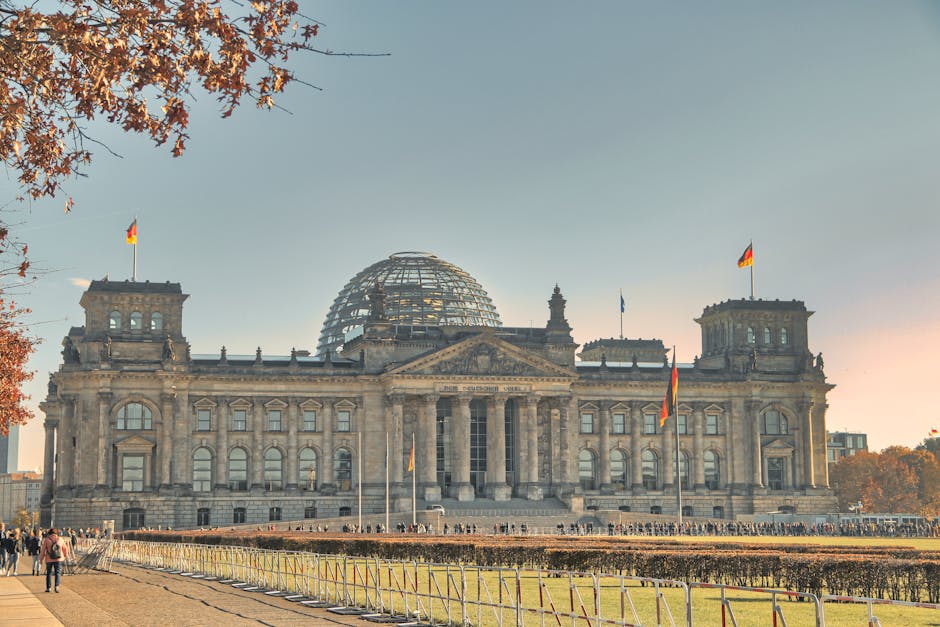 The historic Reichstag Building in Berlin, Germany, featuring a glass dome and autumn foliage.