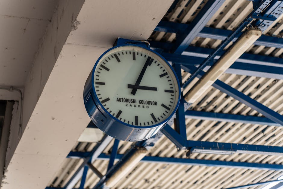 A wall-mounted clock at the Zagreb bus station showing time, under a metallic ceiling.