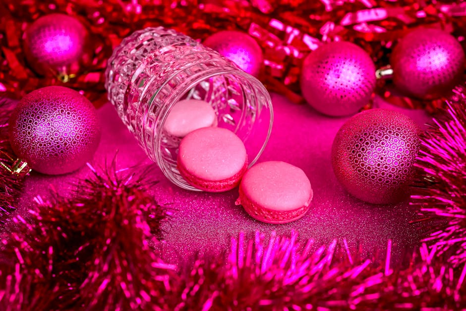 Pink macarons amidst glittering pink ornaments and tinsel, conveying festive joy.
