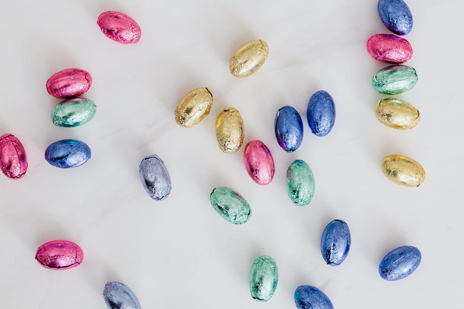 Assorted colorful foil-wrapped Easter chocolate eggs on white background.