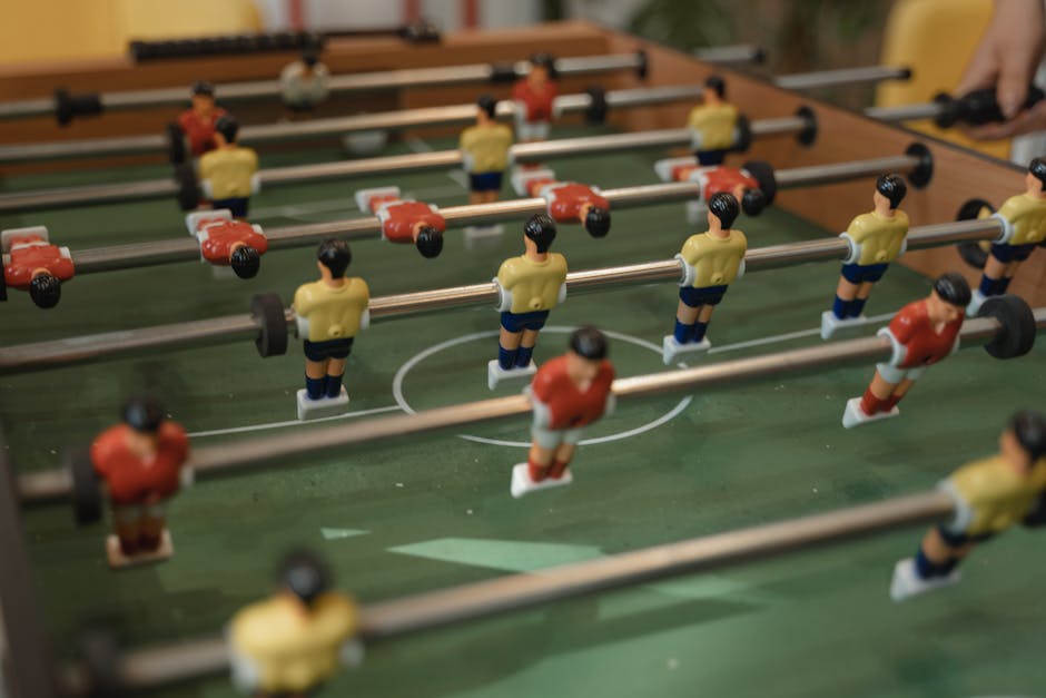 Close-up of a foosball table with soccer figurines in intense gameplay action.