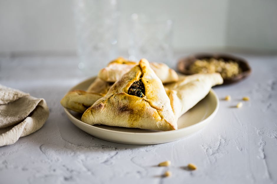 A close-up of freshly baked triangular pies on a table, emphasizing the savory filling.