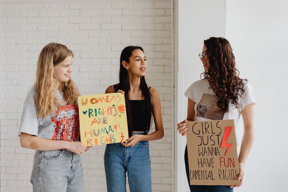 Three women holding advocacy signs supporting women's rights, indoors.