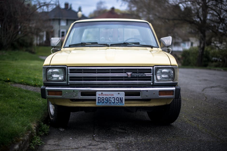 A classic yellow Toyota pickup truck parked on a quiet suburban street with Washington license plates.